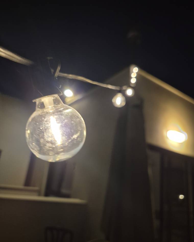 The G40 string running lit across our porch at night, patio umbrella silhouetted behind